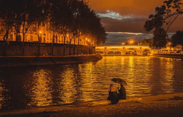 Rencontres Paris : créer des liens authentiques dans la capitale française 4 Couple se promenant le long de la Seine au coucher du soleil
